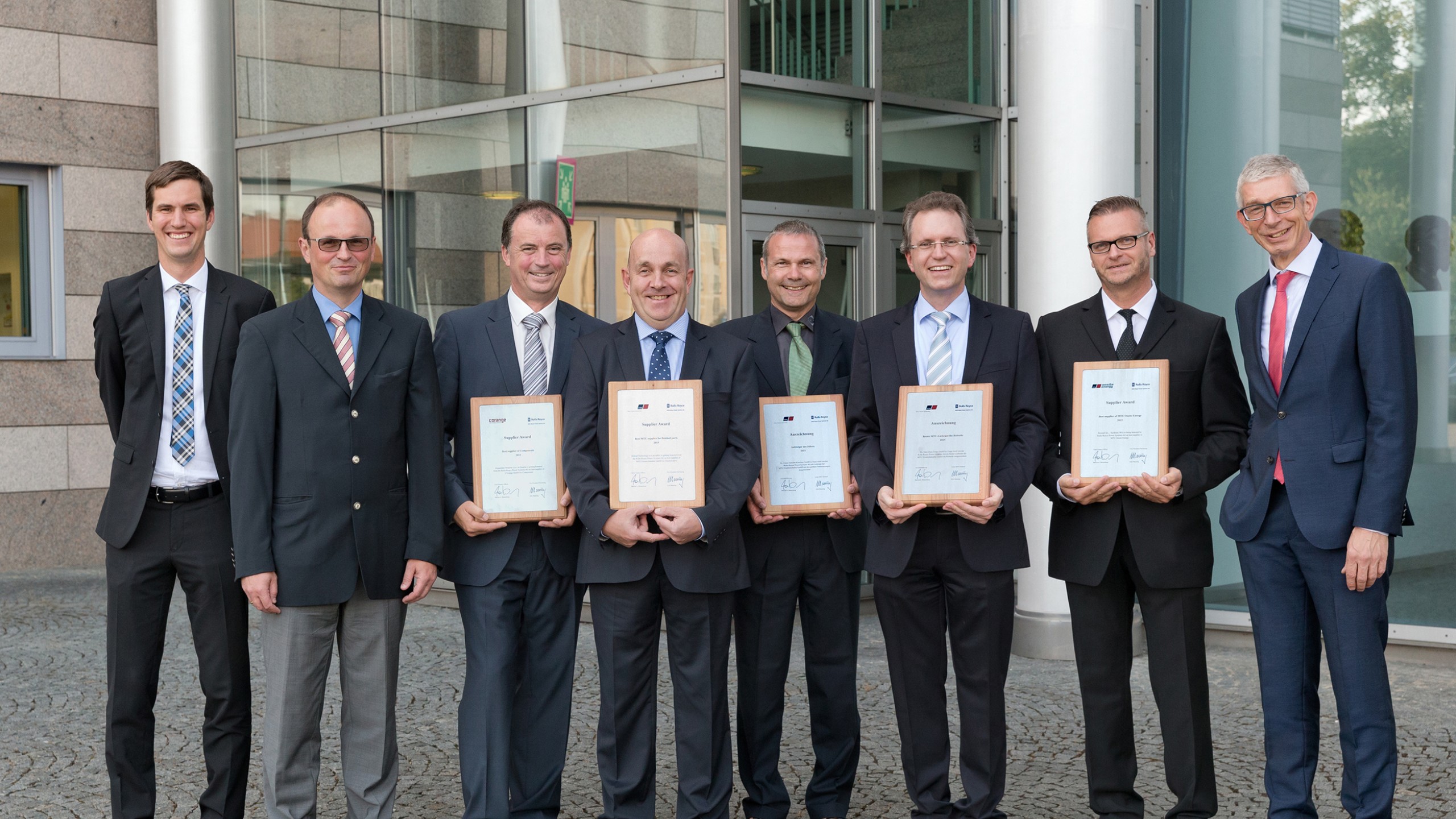 Group of people standing side by side holding plaques to indicate  winning Supplier of the Year award from Rolls Royce MTU