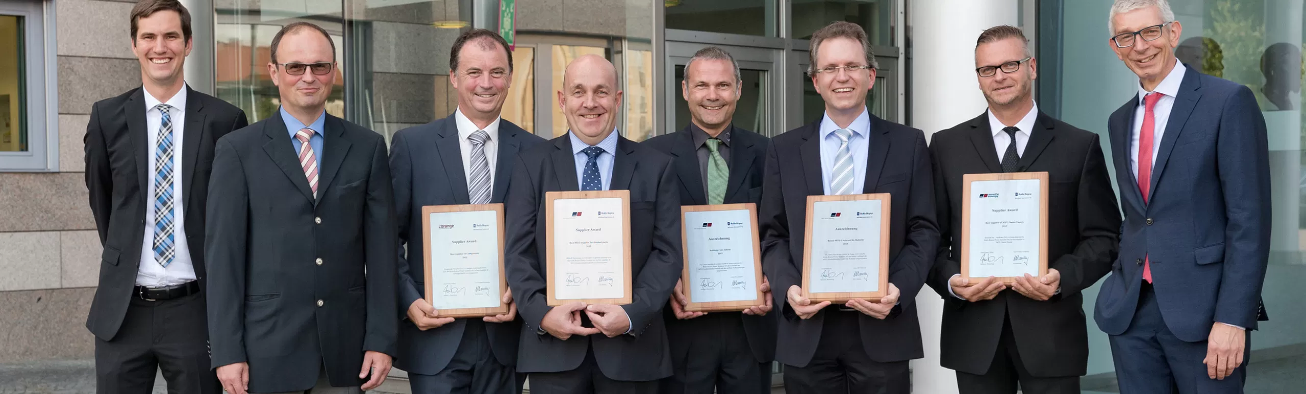 Group of people standing side by side holding plaques to indicate  winning Supplier of the Year award from Rolls Royce MTU