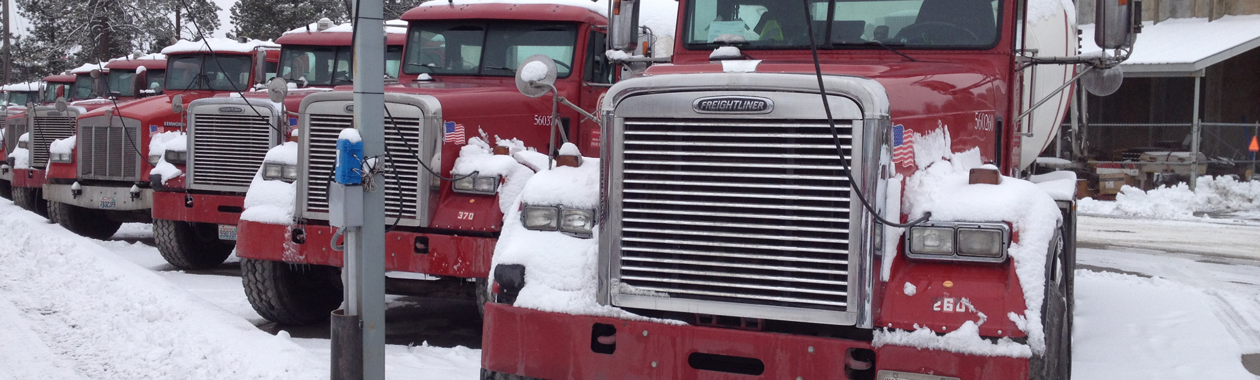 Heavy duty truck parked in snowy weather with a power cord attached  to it for heating the engine while not running