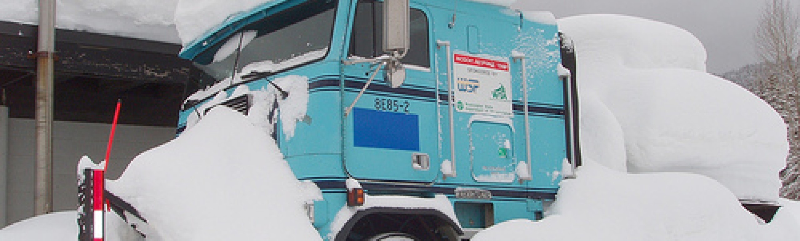 Washington state department of transportation snow plow parked  with large amount of snow on top of the passenger cab