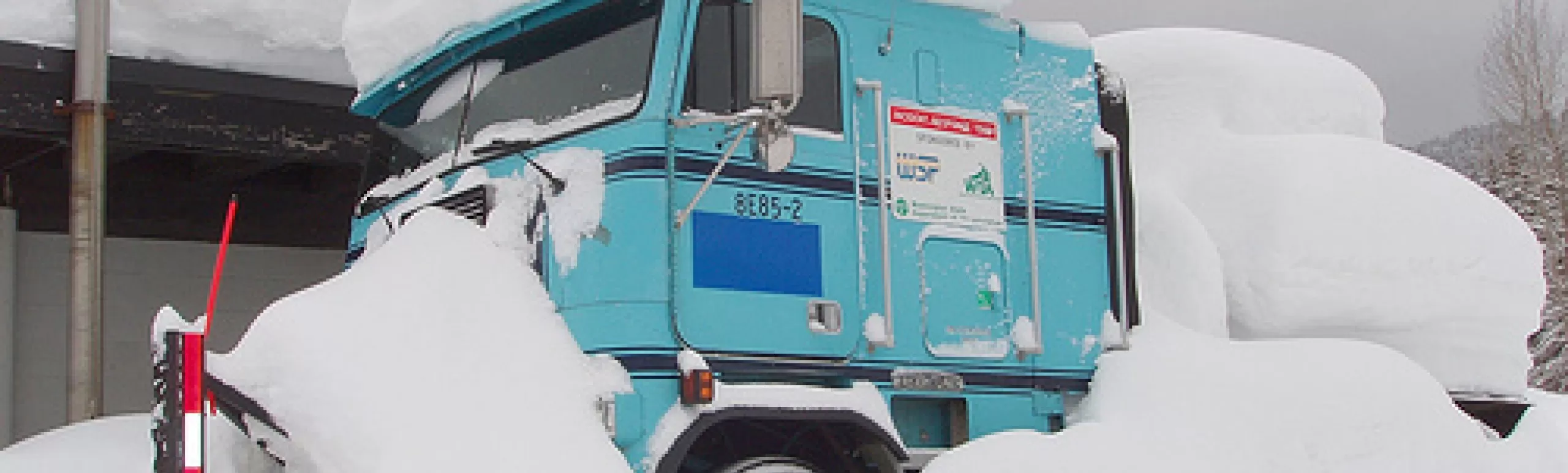 Washington state department of transportation snow plow parked  with large amount of snow on top of the passenger cab